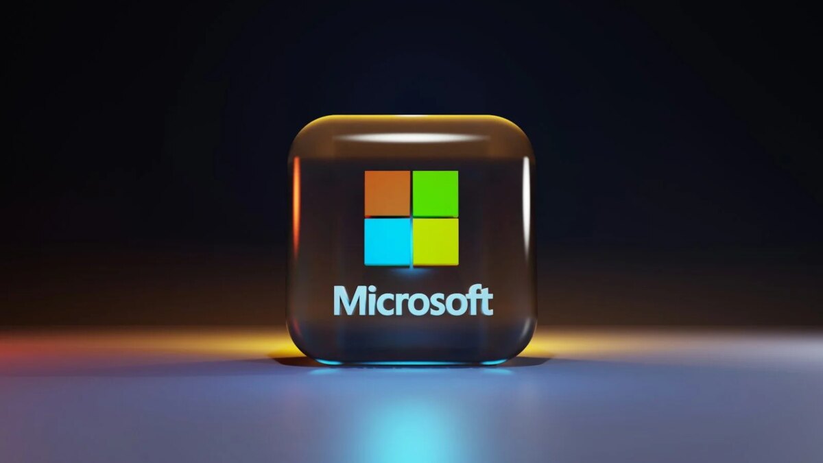 A glossy glass cube with the Microsoft logo on a dark surface